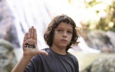 Junge mit der Aufschrift "Stop" auf der Hand