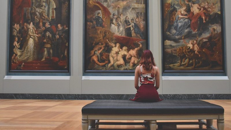 Frau sitzt in Gemäldegalerie