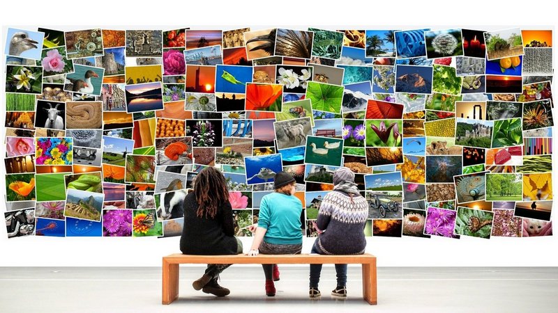 Personen sitzen vor einer Wand mit Bildern 