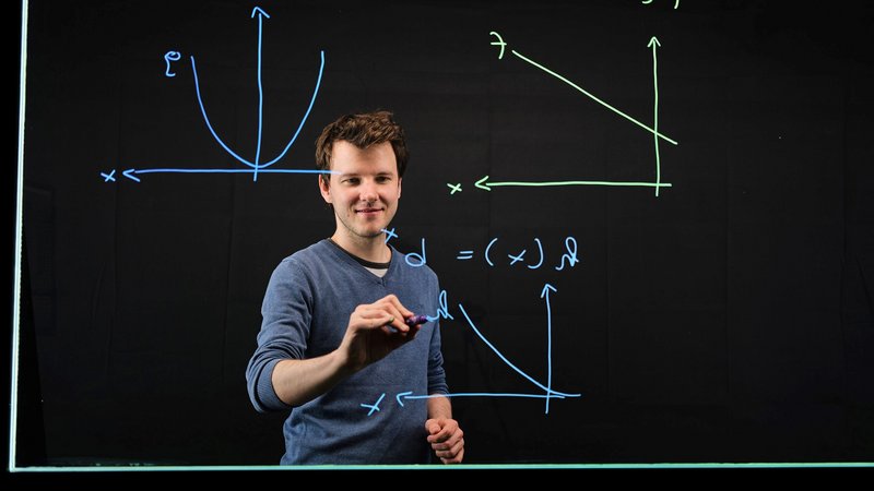 Ein Mann zeichnet mathematische Formeln auf eine Tafel