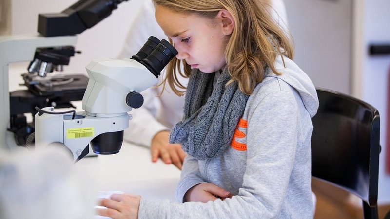 Mädchen sieht durch ein Mikroskop