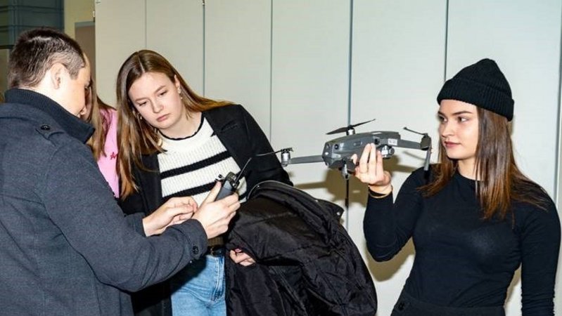 Jugendliche Mädchen und Lehrer betrachten eine Drohne 