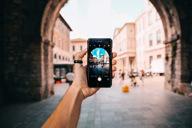 Person fotografiert Stadtbogen mit Smartphone 
